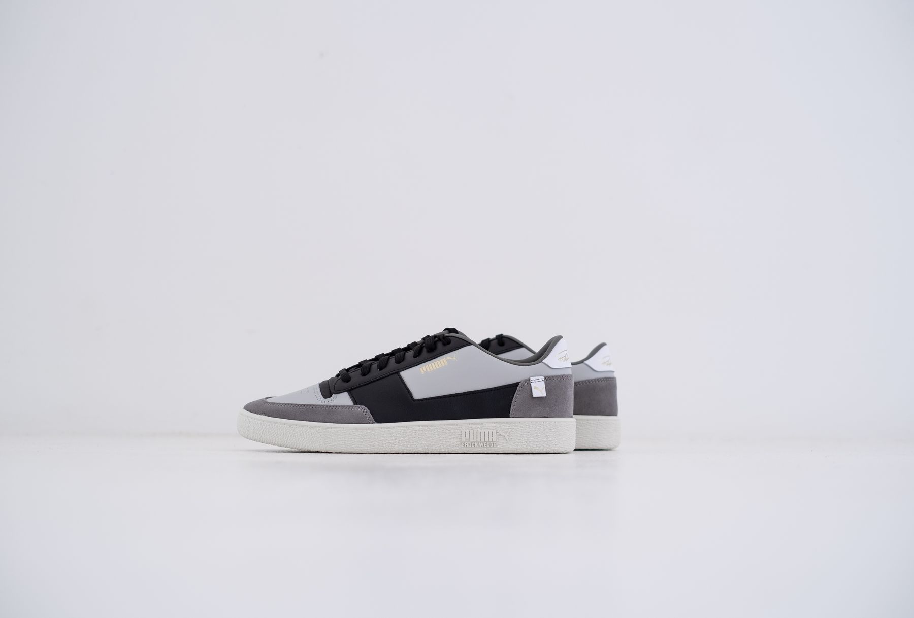 A pair of gray and black sneakers photographed on a light studio surface.